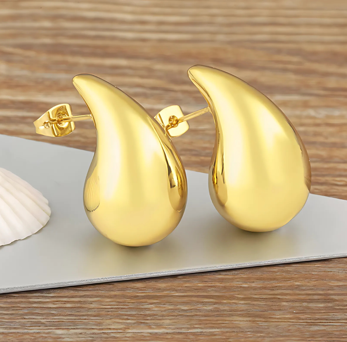 The Infinite Shop gold teardrop stud earrings with smooth polished finish, displayed on a wooden background for an elegant minimalist look
