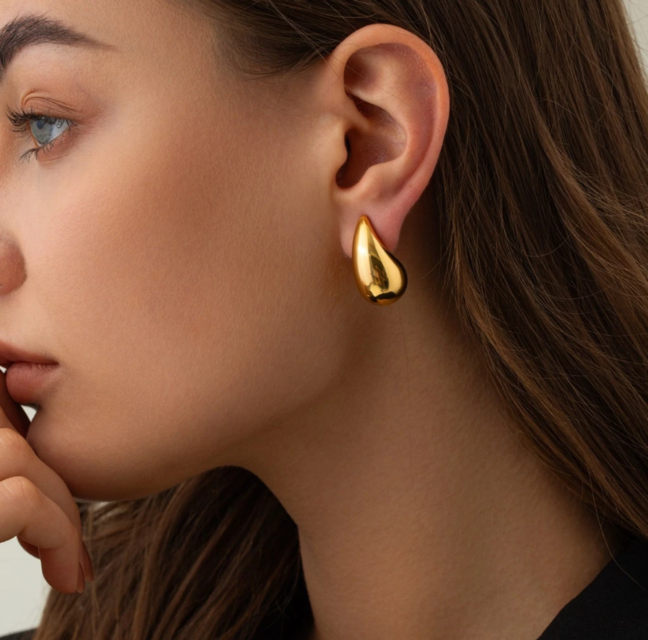 The Infinite Shop gold teardrop earrings worn by a woman, featuring a smooth polished finish and elegant minimalist style