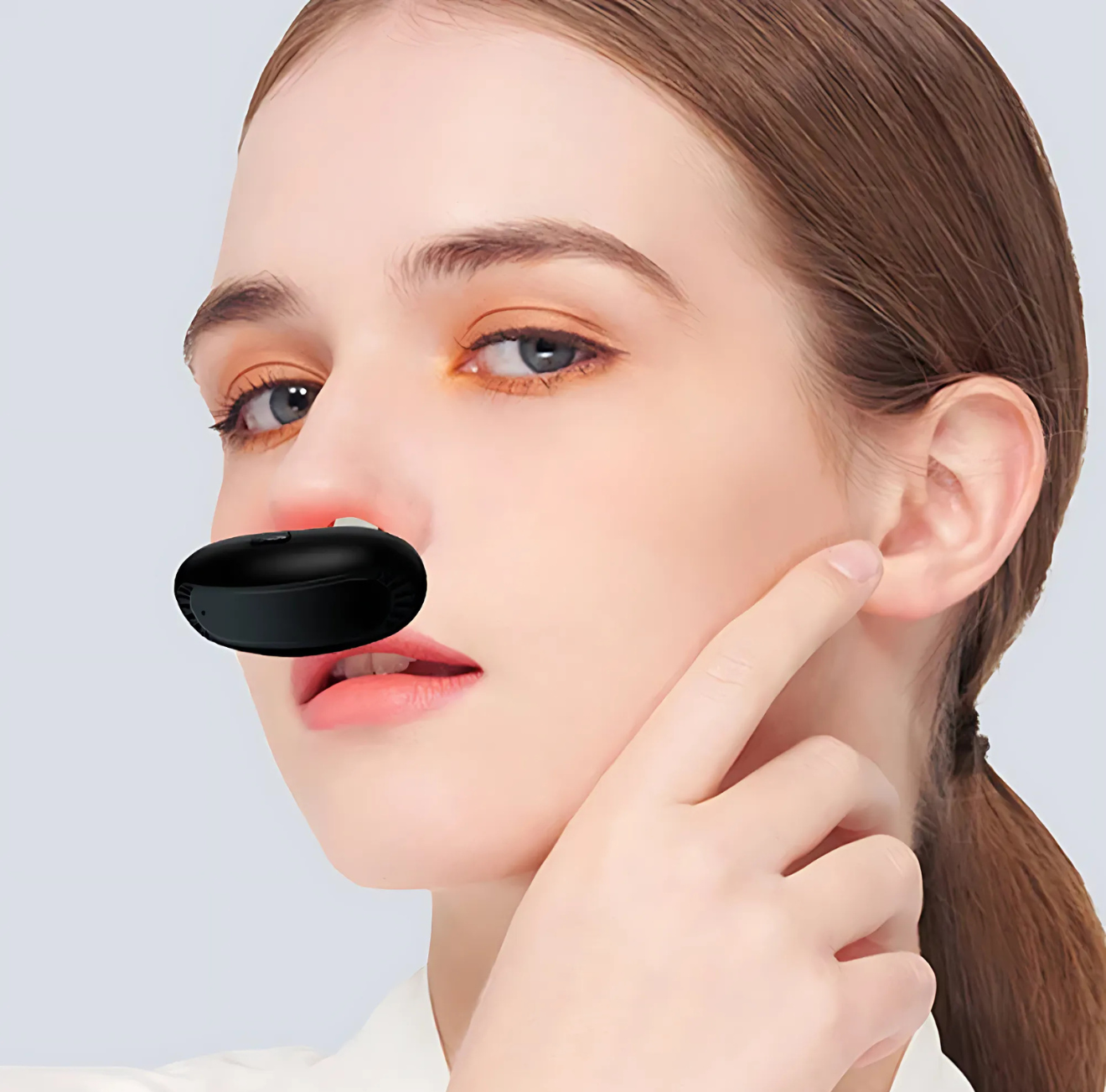 Woman demonstrating The Infinite Shop nasal therapy device for sinus relief, showing black handheld design positioned at nostrils for red light treatment