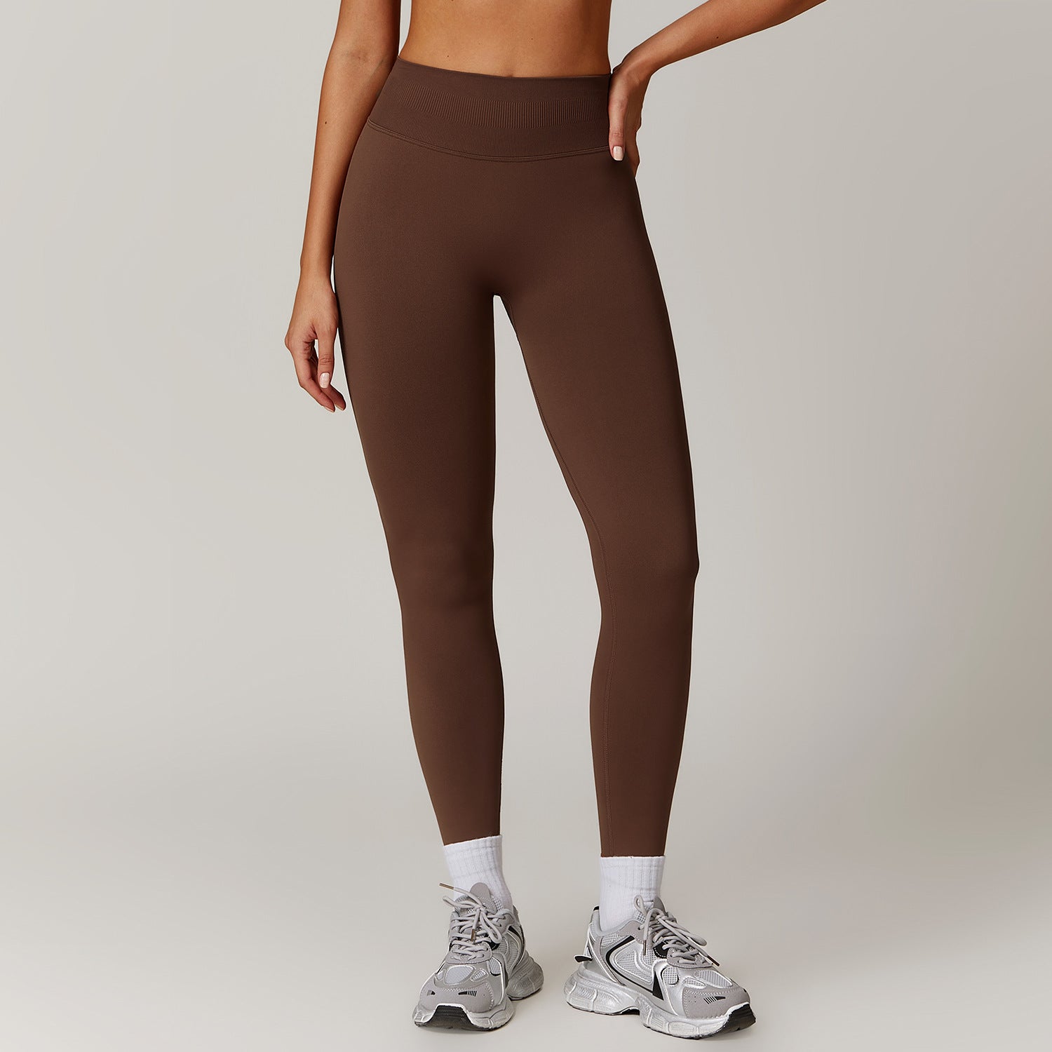Brown Seamless High-Rise Yoga Pants by The Infinite Shop, designed for comfort and flexibility, shown on model standing in athletic sneakers.