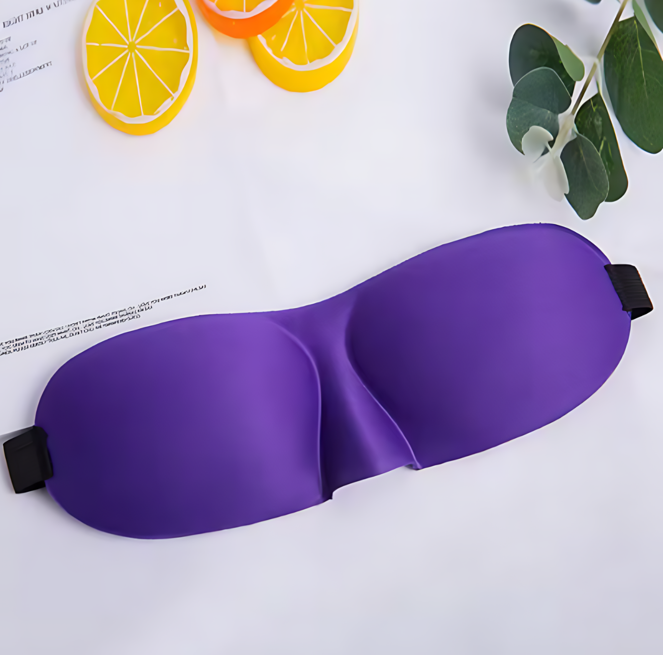 Purple sleep mask on a white surface with colorful slices of fruit and green leaves.