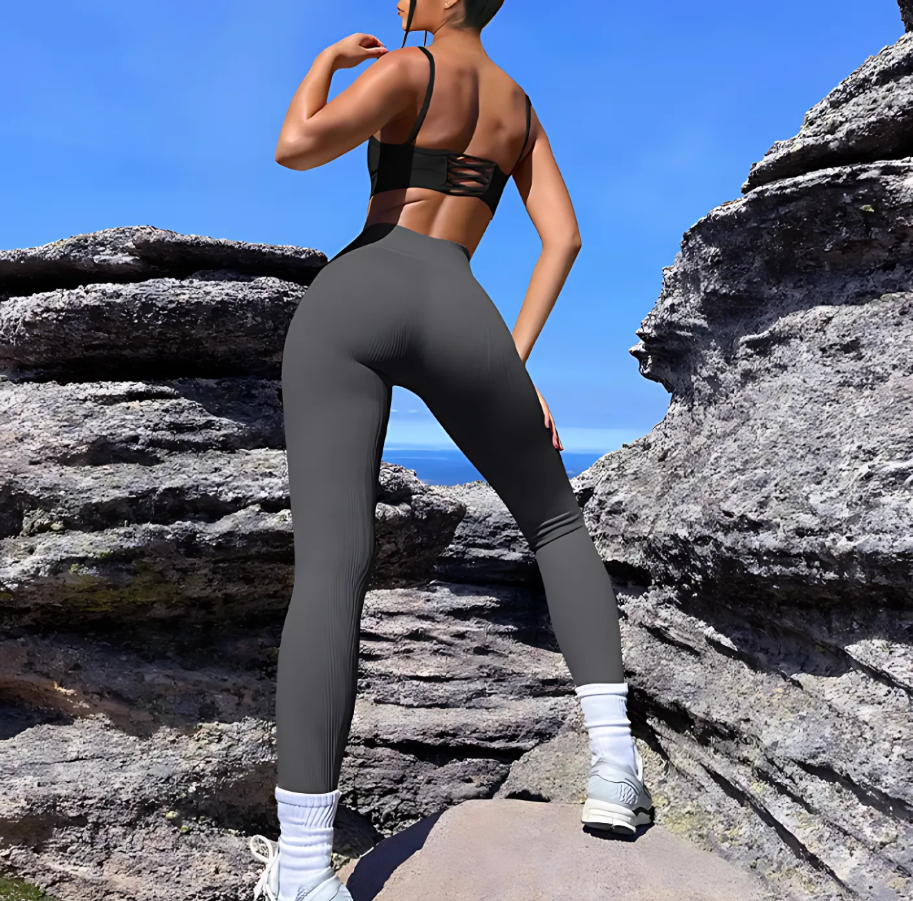 Woman wearing gray V-Shaped High Waist Yoga Pants from The Infinite Shop outdoors on rocky terrain.