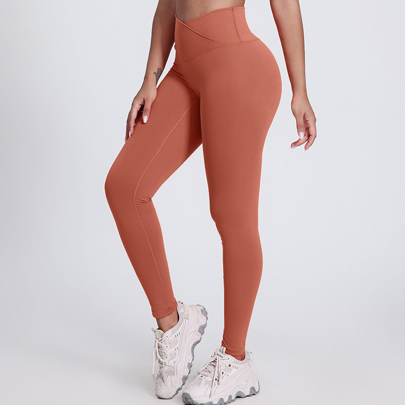 Rust-colored V-Shaped High Waist Yoga Pants from The Infinite Shop shown from front side view with white sneakers.